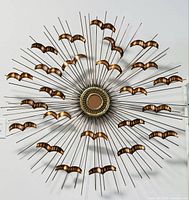 Full front view of circular sculpture showing radiating rods and metal accents