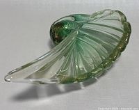 Side view of the green and gold flecked Italian Murano glass cornucopia bowl showing its curved horn shape and ribbed texture.