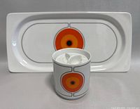 Front view of porcelain sugar bowl and matching rectangular tray with abstract orange and yellow circle motif on white background
