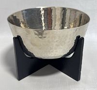 Front view of hammered silver bowl on black stand showing hammered texture and reflective surface