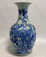 Front view of the blue and white porcelain vase showing raised dragon motif and foliage details.