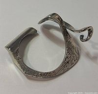 Photo showing the full sculptural form and texture of the Guy Vidal signed modernist cuff bracelet from an angled side view.