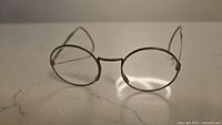 Front view of small round antique wire frame glasses showing round lenses and wire nose bridge.