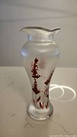 Front view of iridescent frosted glass vase with red floral decoration and flared rim.