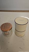 Bath & Body Works Winter Sage candle with copper textured lid and Jo Malone Green Tomato Vine candle box side by side.