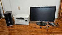 Photo showing Dell Inspiron tower, Samsung SCX-3405W printer/scanner, and Samsung 27" monitor with cables on wooden floor