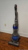 Full front view of Dyson DC29 multi floor upright vacuum showing upright handle, clear dust bin, and brush head in front.