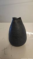 View of the handmade pottery vase showing the shape, size, and dark matte finish with textured rings.