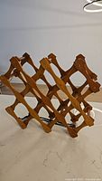 Side angle view of the vintage wooden collapsible wine rack showing the lattice structure and bottle slots.