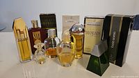 Full view of all 10 perfume and cologne bottles together, some boxed, some loose on white surface