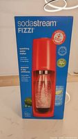 Boxed Sodastream Fizzi sparkling water maker in red showing front and branding
