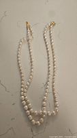 Full view of the double-stranded faux pearl necklace laid flat showing length and pearl sizes