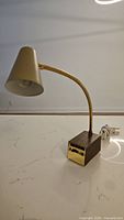 Side view of vintage Ohm Rite Electric Ltd. desk lamp showing flexible gooseneck, beige lampshade, wood base, and attached power cord.