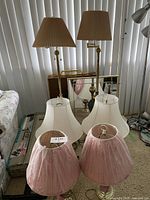 Two pairs of table lamps and two floor lamps with beige pleated shades visible behind.