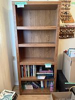 Frontal view of the wooden bookshelf showing all shelves and some books on lower shelves.