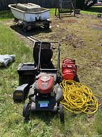 Front view of Craftsman lawnmower with accessories including gas canisters and yellow extension cord