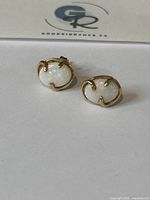 Front view of the pair of 10K gold stud earrings with white opal stones on a white background.