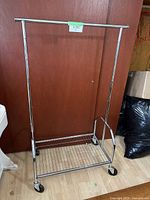 Full front view of the silver metal rack showing adjustable hanging rod and caster wheels.