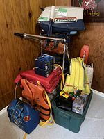 Overview of lot showing Evinrude motor, power pack, life jackets and accessories