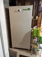 White upright freezer standing on floor, showing full front view.