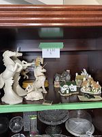 Display shelf with unicorn figurines and David Winter village cottages arranged together