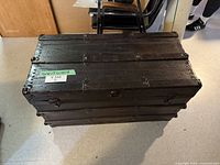 Full view of vintage black metal trunk showing robust design and riveted details.