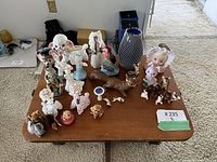 Wooden table displaying multiple assorted vintage figurines including animals and doll heads in various colors and sizes.
