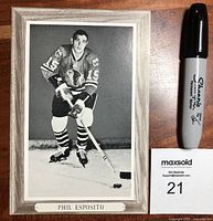 Front view of black and white Phil Esposito hockey photo on cardboard, next to marker for scale