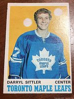 Front of card showing Darryl Sittler in Toronto Maple Leafs uniform on yellow background, white border