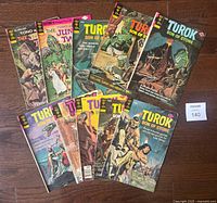 Full lot of 10 Gold Key comics displayed on wooden floor, includes 8 "Turok Son of Stone" and 2 "Tono & Kono" comics showing front covers with adventure scenes including dinosaurs and jungle action.