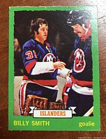 Front of the 1973-74 Billy Smith rookie hockey card with a green border, player image, and team info.