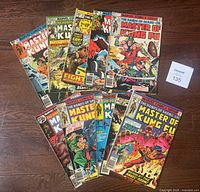 Nine Marvel 'Master of Kung Fu' comic books laid out on a wooden floor showing covers with various martial arts action scenes, vintage comic book style from 1974-1980.