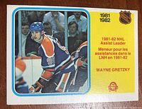 Front face of the 1982-83 OPC hockey card showing Wayne Gretzky in Edmonton Oilers uniform with the title and stats for NHL Assist Leader 1981-82.