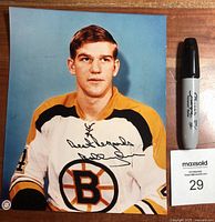 Full front view of the autographed color photo of Bobby Orr wearing Boston Bruins jersey, alongside a black Sharpie for scale.