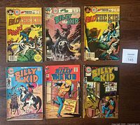 Lot of 6 Charlton Billy The Kid comic books shown flat on wood floor. Covers show Western illustration artwork with wear consistent with age.