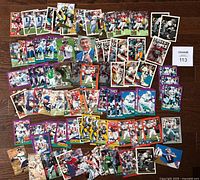 Photo showing a variety of 1994 NFL football cards spread on a wooden floor. Visible cards include multiple team players such as Green Bay Packers, Dallas Cowboys, Miami Dolphins, and others with player action shots and inserts.