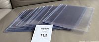 Photo of 20 clear rigid hard plastic card holders stacked and fanned slightly on a surface showing their transparent quality and uniform size.