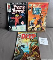 Lot of three comic books Star Brand, Lady Cop, and The Deep together on table