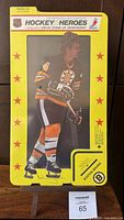 Full view of sealed yellow bordered standup featuring Bobby Orr in Boston Bruins uniform on laminated cardboard within original packaging.