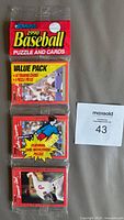 Front view of sealed 1990 Donruss Baseball card rack pack featuring puzzle and cards, showing puzzle artwork and player image.