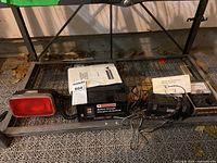 Wide shot showing all three items: battery charger, red light with coiled cord, and multi-tester