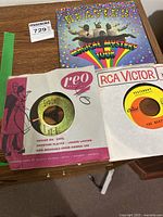 Close-up of two 45 rpm vinyl singles, one on RCA Victor featuring the song "Yesterday" and the other on REO Records in red & pink sleeve.