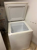 Chest freezer with open lid showing interior wire basket and inner compartment.