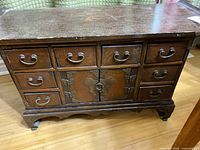 Front view of small wooden cabinet with eight drawers and central doors on bracket feet