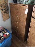 Full view of highboy dresser with woodgrain finish and six drawers with worn handles.