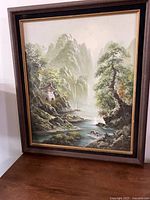 Full view of the framed landscape painting showing the river valley, cliffs, trees, and pagoda tower.