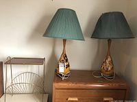 Pair of bedroom table lamps with green pleated shades, ceramic and mottled bases on a wood cabinet.