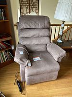 Front view of brown upholstered lift chair with remote attached