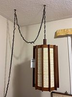 Full view of hanging lamp showing wooden slats, fabric shade, and chain