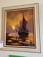 Full view of framed sailboard painting showing sailboat, shore, and two figures at sunset.